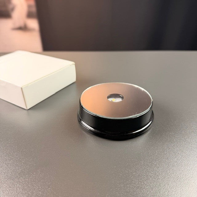 Svart rund batteriljusbas bredvid asken