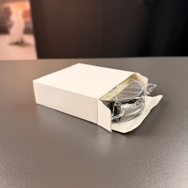 Svart rund batteriljusbas i vit ask