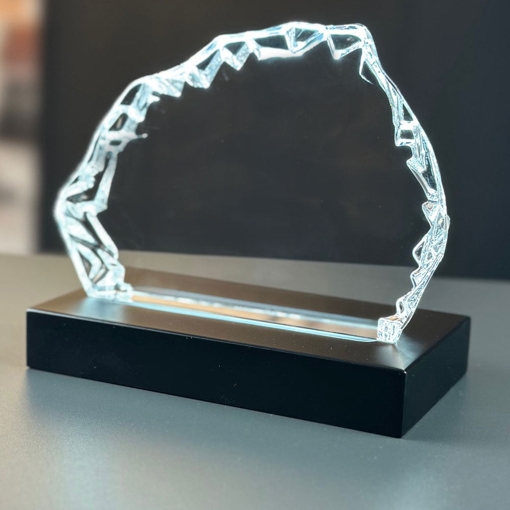 Isbergsformad glasblock framifrån på tänd mattsvart lyxljusbas 9x16 cm