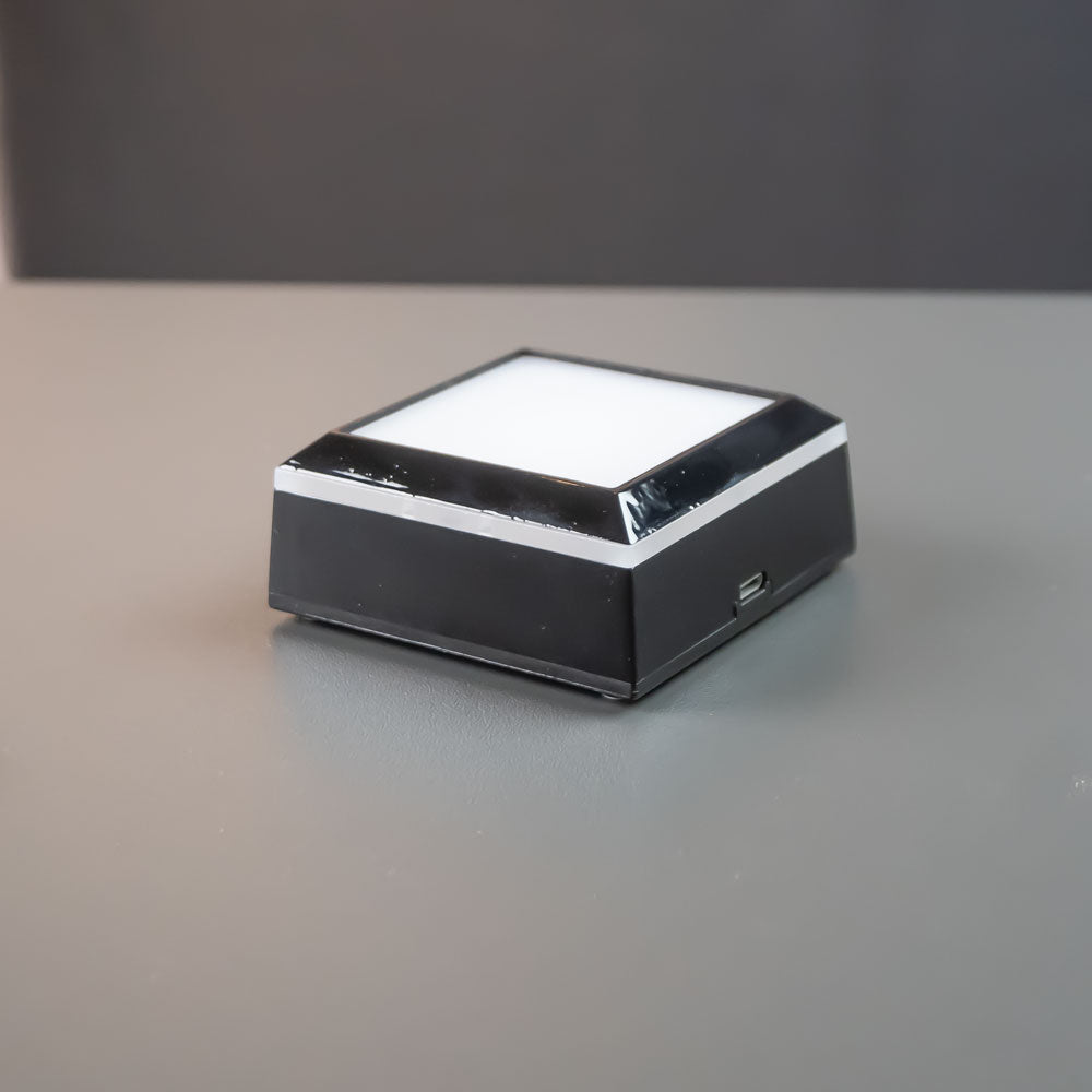 Svart kvadratisk ljusbas 7×7 cm med tänt vitt LED-ljus