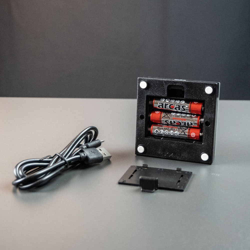 Svart batteriljusbas med batterifack och USB-kabel