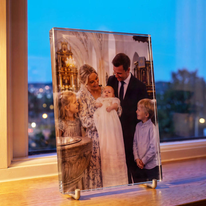 Printglas med färgtryck av familjefoto från ett dop, sett från sidan i ett fönster