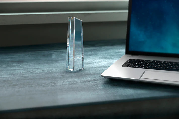 Hög obelisk award i kristallglas på ett skrivbord