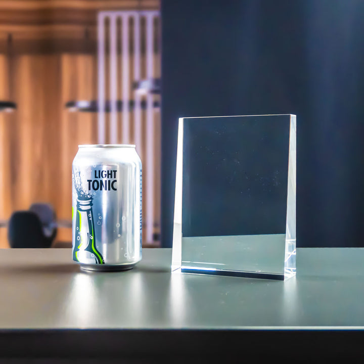 Prism award bredvid en läskburk för storleksjämförelse, stående