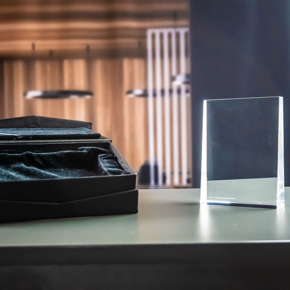 Prism award i klart kristallglas framför den öppna svarta presentasken