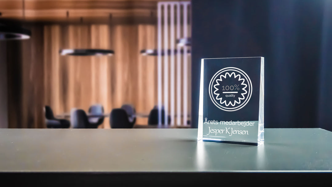 Prism award med 2D-graverad logga och text i en kontorsmiljö
