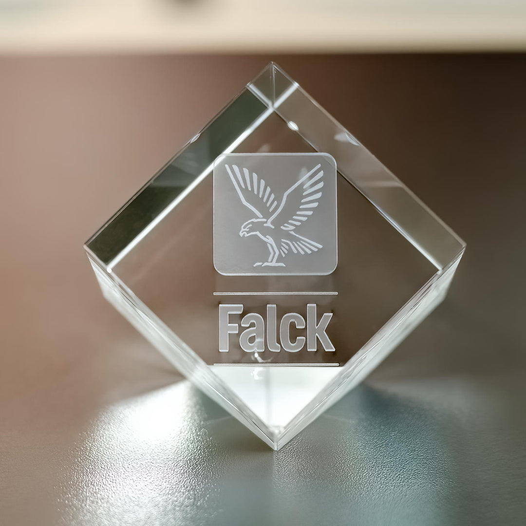 Glaskub med avskuret hörn och 3D-graverad logga sedd framifrån