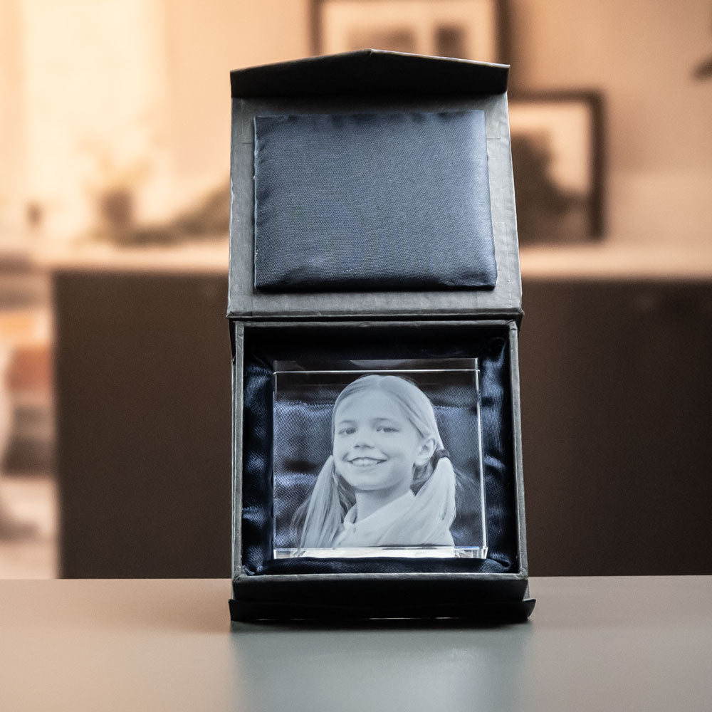 Kvadratisk glasblock med graverad flicka i öppen svart presentask