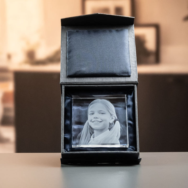 Kvadratisk glasblock med graverad flicka i öppen svart presentask