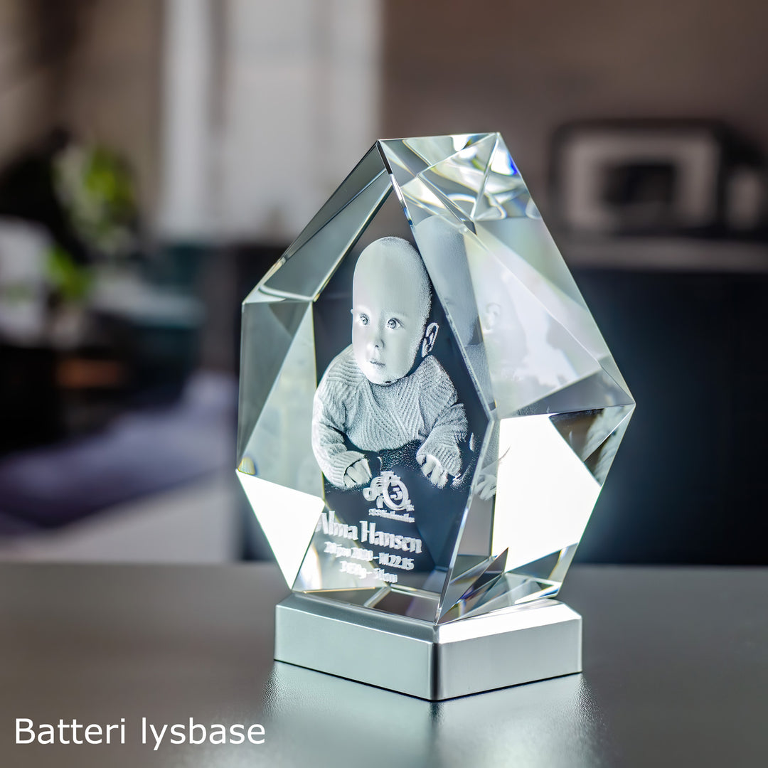 Hög isbergsformad glasblock med graverad bebis på en batteriljusbas i metall