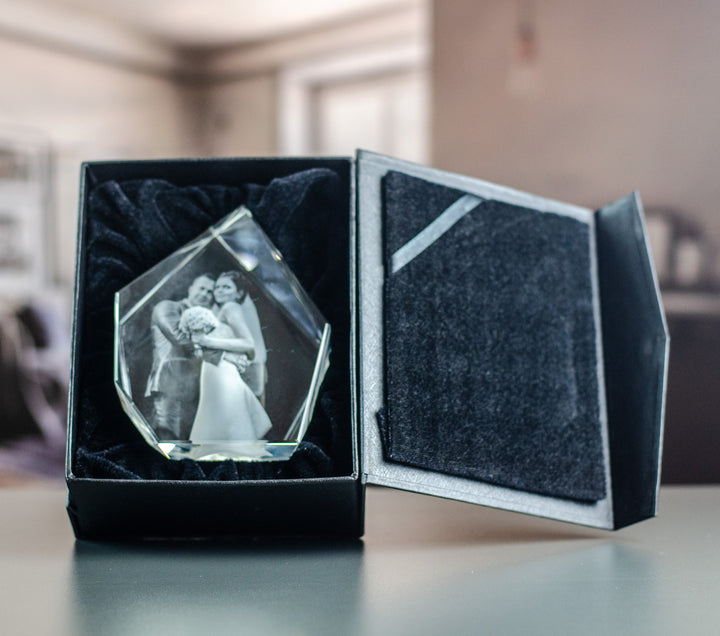 Hög isbergsformad glasblock med brudpar i öppen svart presentask